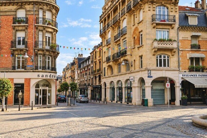 A cobblestone street lined with historic buildings, a boutique named 'sandro', and a patisserie 'ECLAENGE Patisserie'. 4