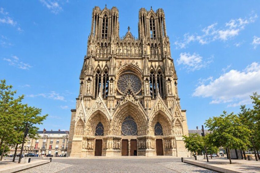 A large Gothic cathedral with intricate architecture, a prominent clock, and a clear blue sky. 2