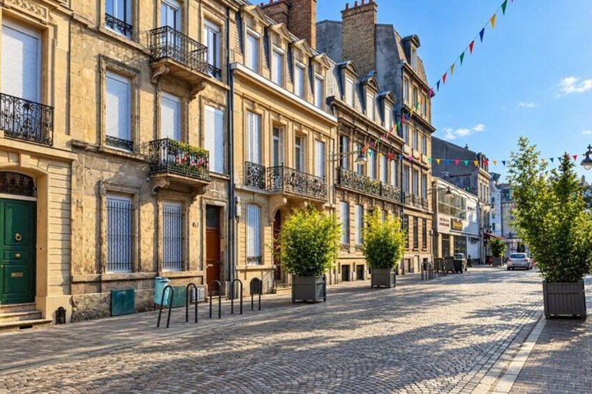 A cobblestone street lined with historic buildings, potted plants, and a clear blue sky. 5