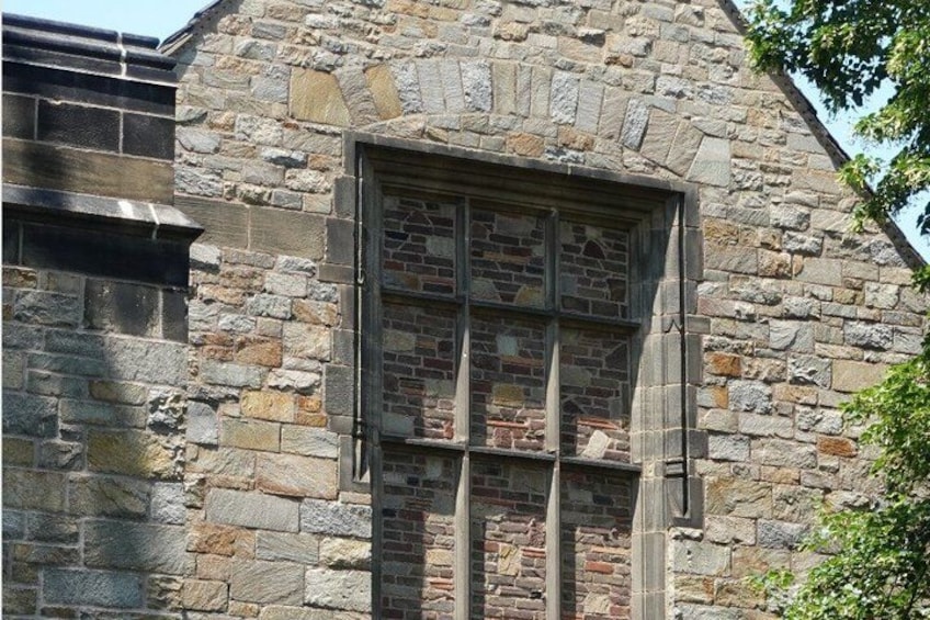 A stone building with a window featuring a grid pattern of bricks. 3