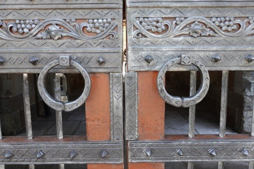 Ornate metal gates with decorative patterns and circular rings. 4
