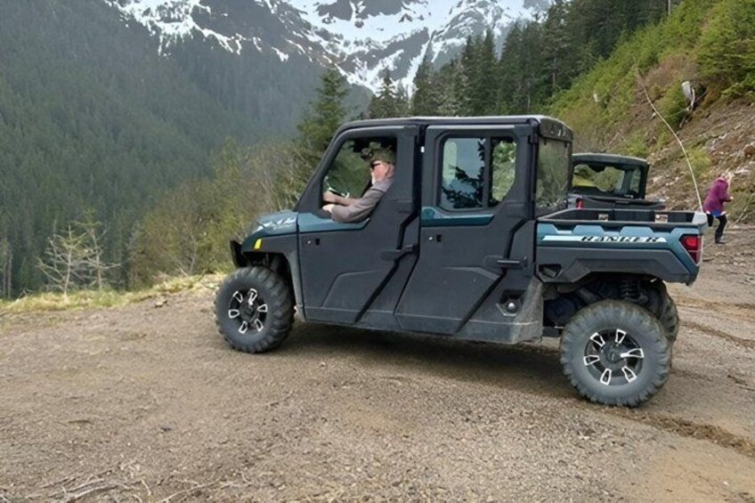 A black utility vehicle parked on a dirt path with a mountainous landscape in the background. 2