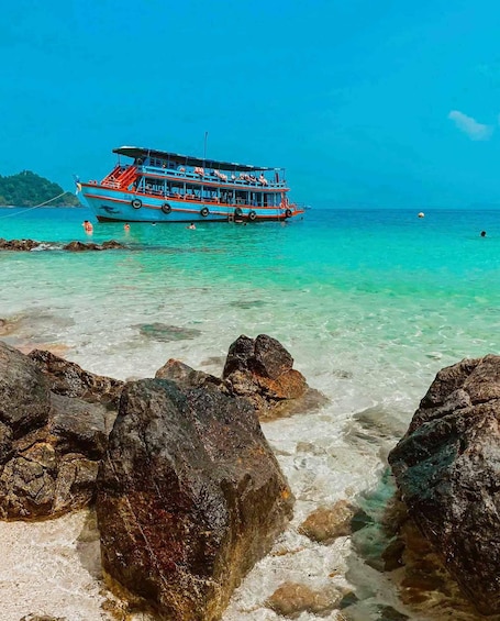 A boat anchored near a rocky shore with clear turquoise water. 5