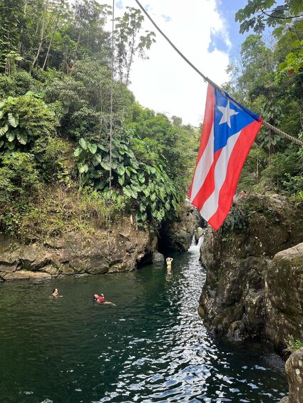 A flag, a waterfall, and people swimming in a river. 3