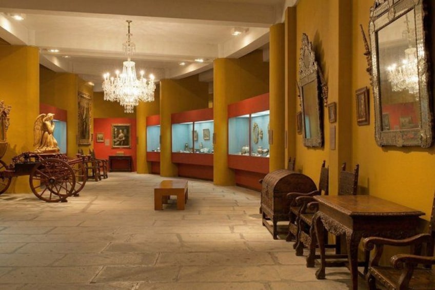 An interior with a chandelier, wooden furniture, and display cases. 5