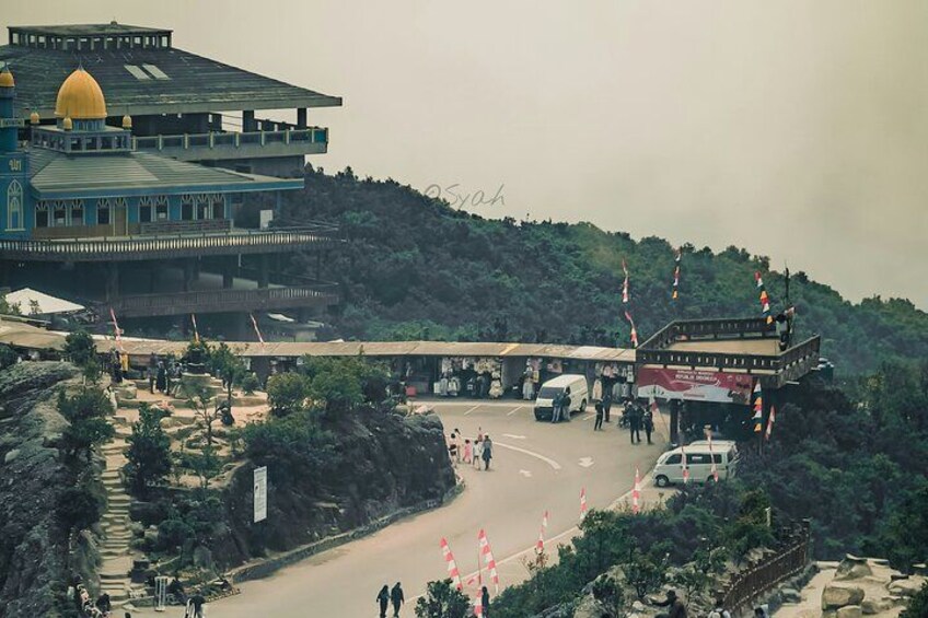 A road leading to a large building with a dome, a bus stop, and flags on poles. 5