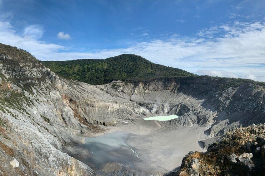 A large open crater with a small lake in the center, surrounded by rocky terrain and forested hills. 4