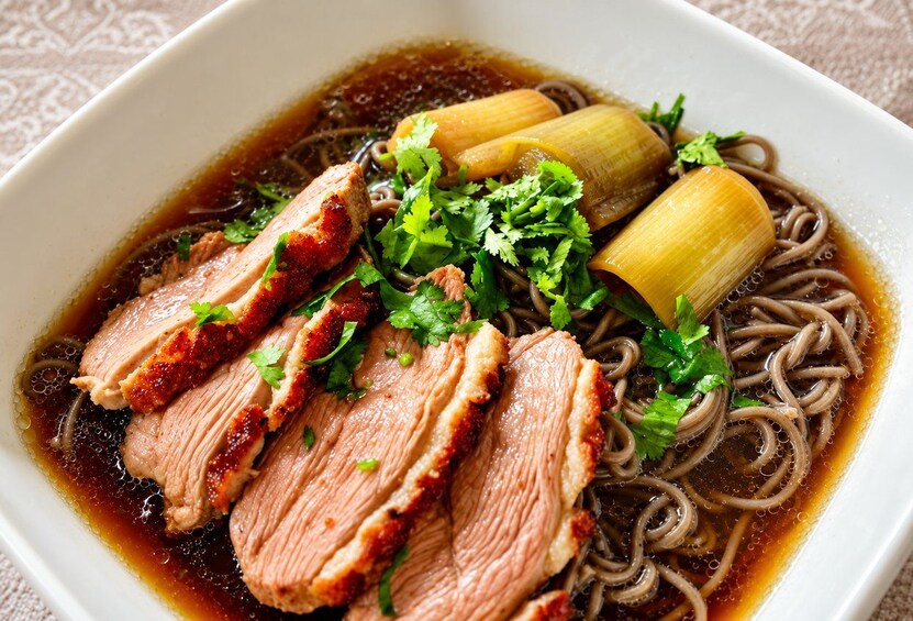 Un bol de soupe contenant des nouilles, des tranches de viande et des légumes. 2