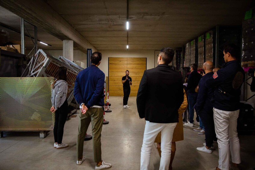 A group of people in a warehouse-like setting with metal structures and wooden panels. 2