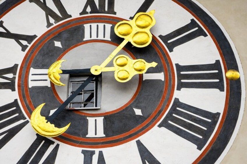 A large clock with Roman numerals and yellow moon shapes. 3