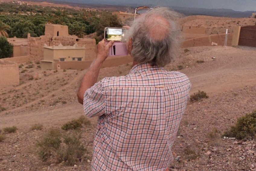 A person taking a photo of a desert landscape with buildings. 5