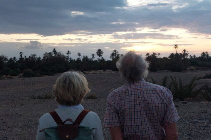 Two people standing on a dirt path with a sunset in the background. 2