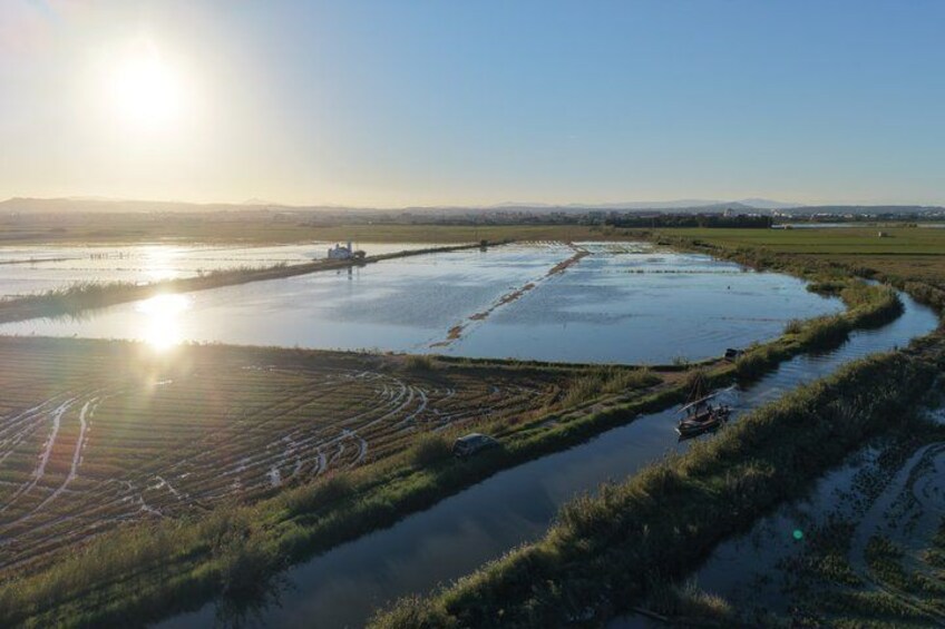 A flooded agricultural field with a boat and a distant structure. 3
