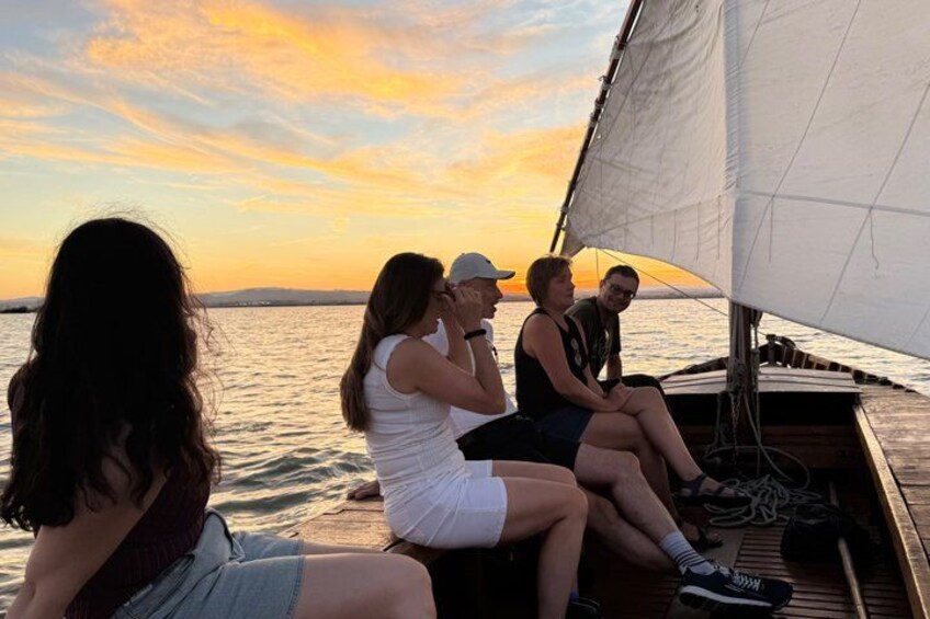 A group of people on a sailboat at sunset. 5