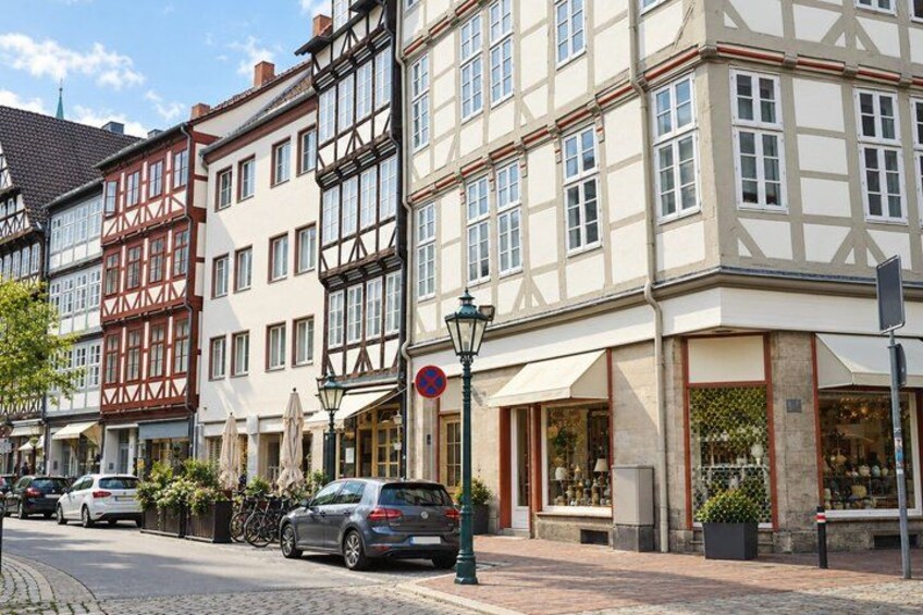 A street with traditional half-timbered buildings, parked cars, and a street lamp. 2