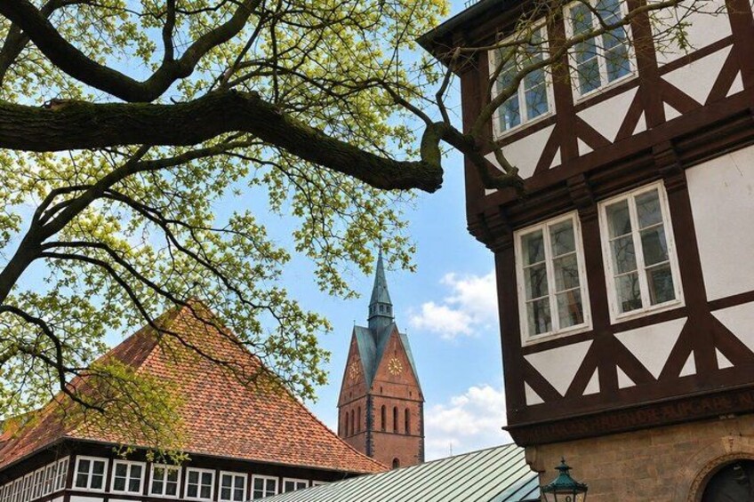 A traditional half-timbered building, a church with a spire, and a tree with green leaves. 3