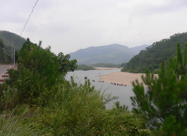 A river with boats, a sandy beach, and mountains in the background. 3