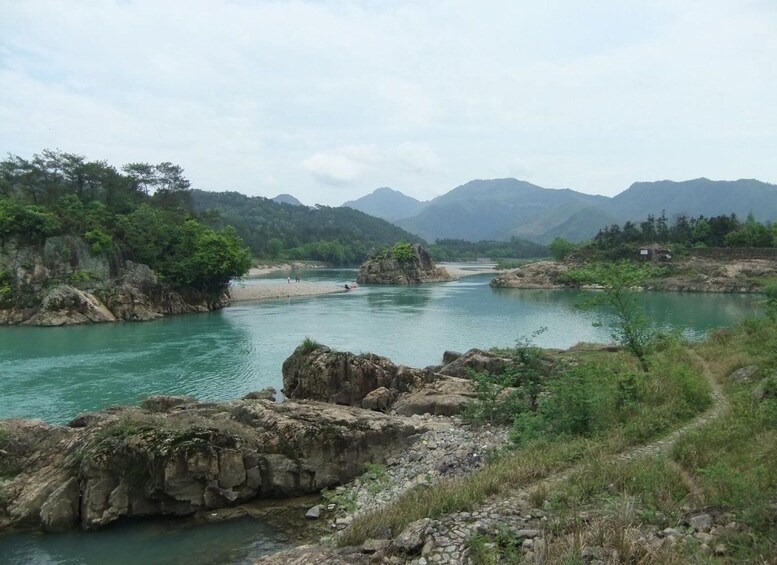 A river flowing through a mountainous landscape with rocky banks and dense greenery. 1