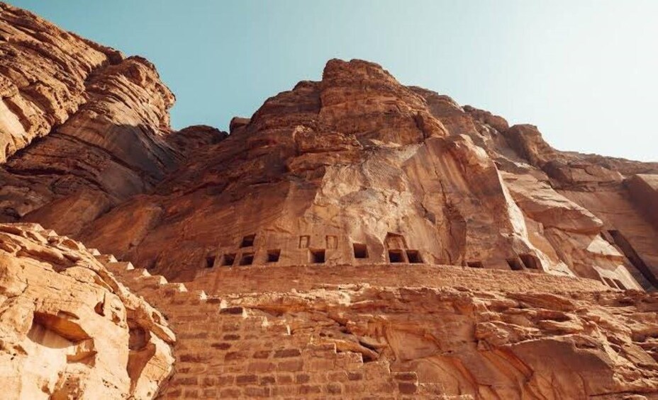A rock formation with carved niches and a staircase leading up to a higher level. 2