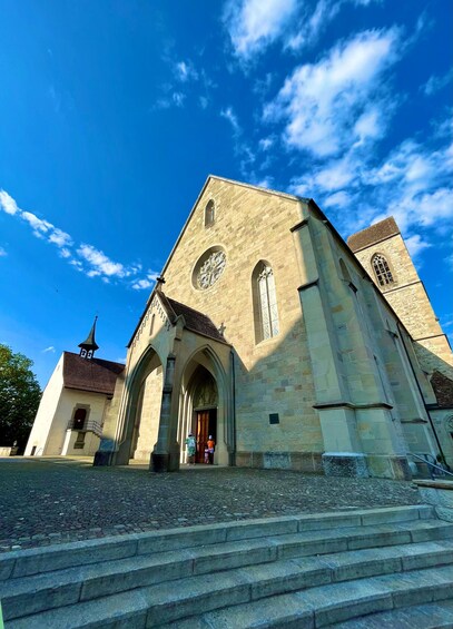 En historisk kirke med et højt tårn, buet indgang og et stort, rundt vindue. 2