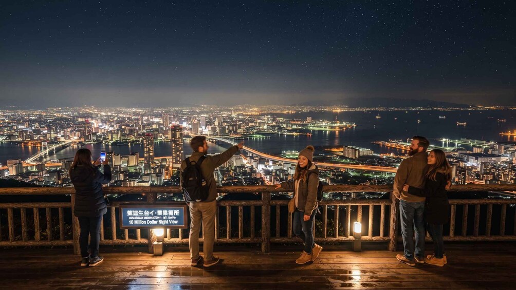 A group of people on a wooden deck overlooking a cityscape at night. 4