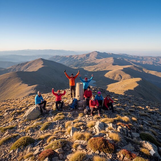 A group of people on a mountain peak with a vast landscape in the background. 3