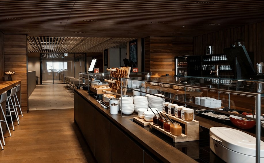 A modern café with a wooden interior, a long counter with various food items, and a coffee machine. 5