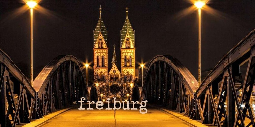 Un pont avec deux tours illuminées et le mot « Fribourg » inscrit en bas. 4