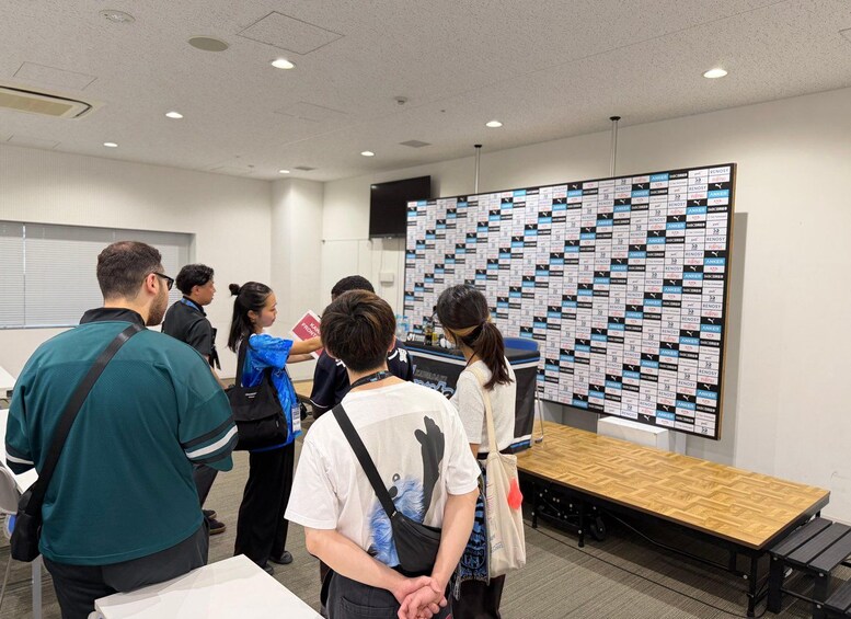 A group of people in a conference room with a large display wall of logos. 2