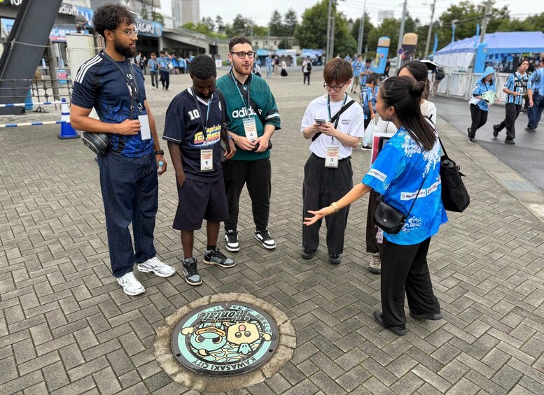 A group of people standing on a paved area with a man in a blue shirt gesturing. 5
