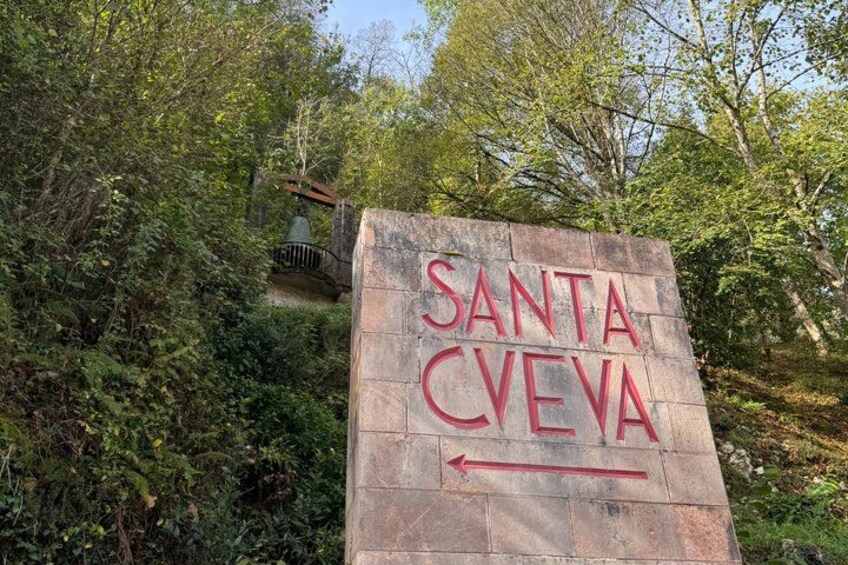 A stone sign with 'Santa Creva' written on it, surrounded by greenery. 2