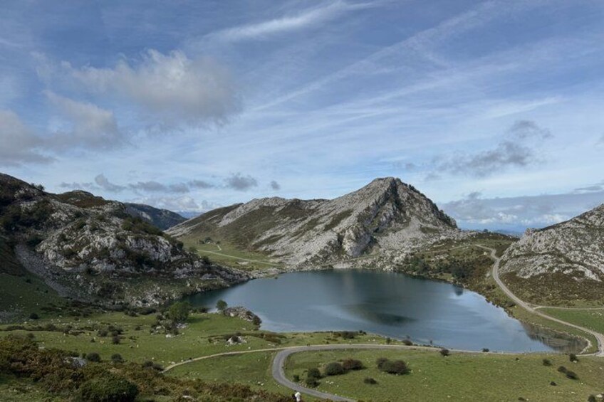 A lake surrounded by mountains, a winding road, and a clear sky. 1