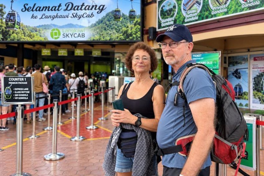 A queue at a transportation hub with a sign for 'Langkawi SkyCab' and a counter for ticketing. 5