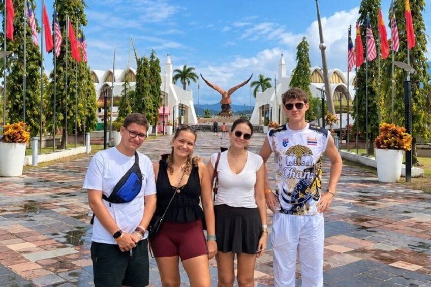 A group of people standing in a plaza with palm trees and flags. 2