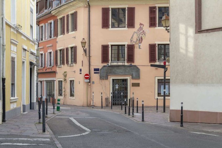 A street with buildings, a no-entry sign, bollards, and a street lamp. 2