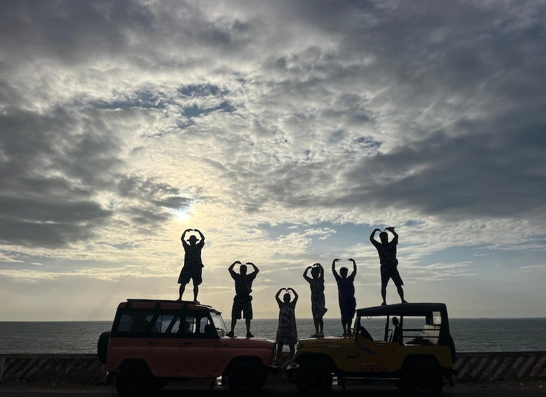 Un groupe de personnes forme des cœurs avec leurs mains, debout sur des véhicules au bord de la mer, au coucher du soleil. 4