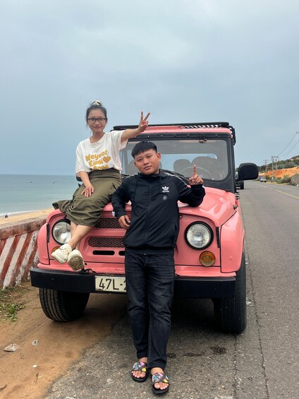 Un véhicule rose est garé au bord de la route, avec une plage en arrière-plan. 5