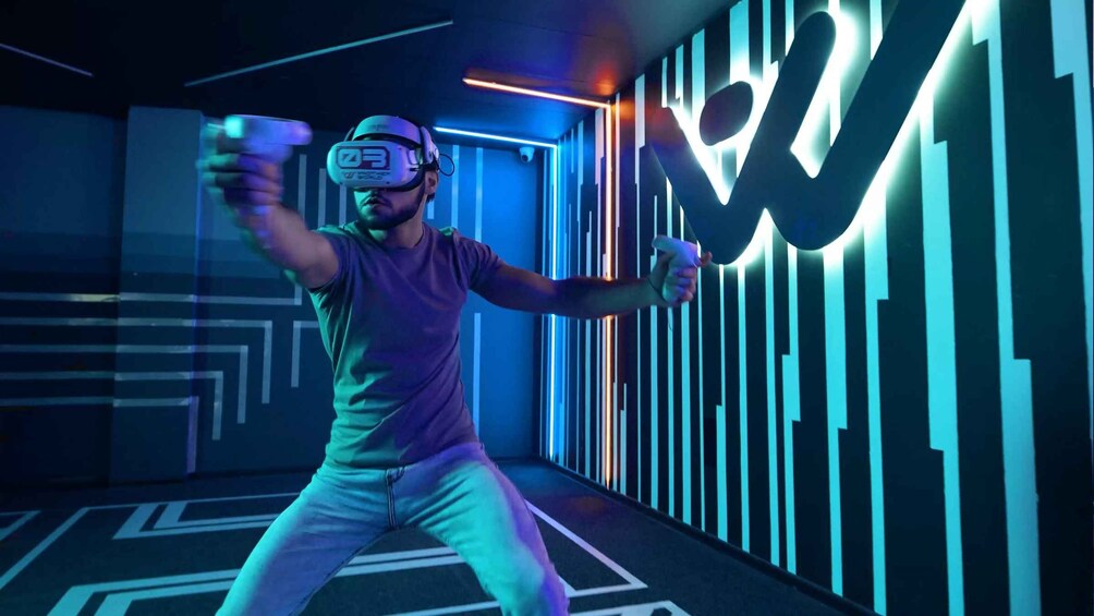 En person med et VR-headset i et rum med et geometrisk mønster på væggen og en neonskilte. 3