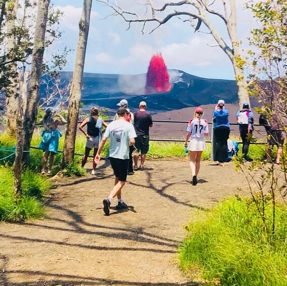 A group of people walking on a path with a volcano in the background. 1