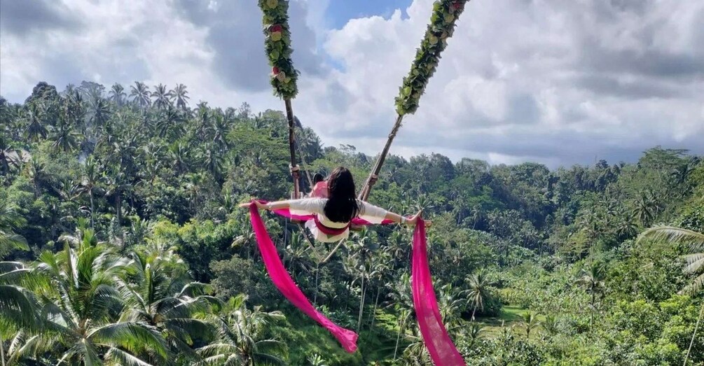 Une personne pratiquant des acrobaties aériennes avec des voiles dans une forêt tropicale luxuriante. 1