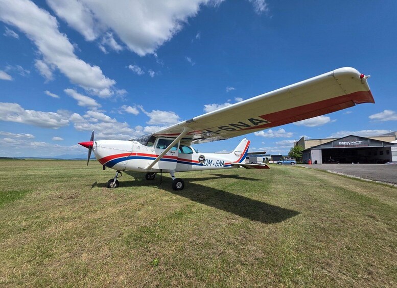 A small propeller airplane with registration DM-SNA parked on a grassy field. 2
