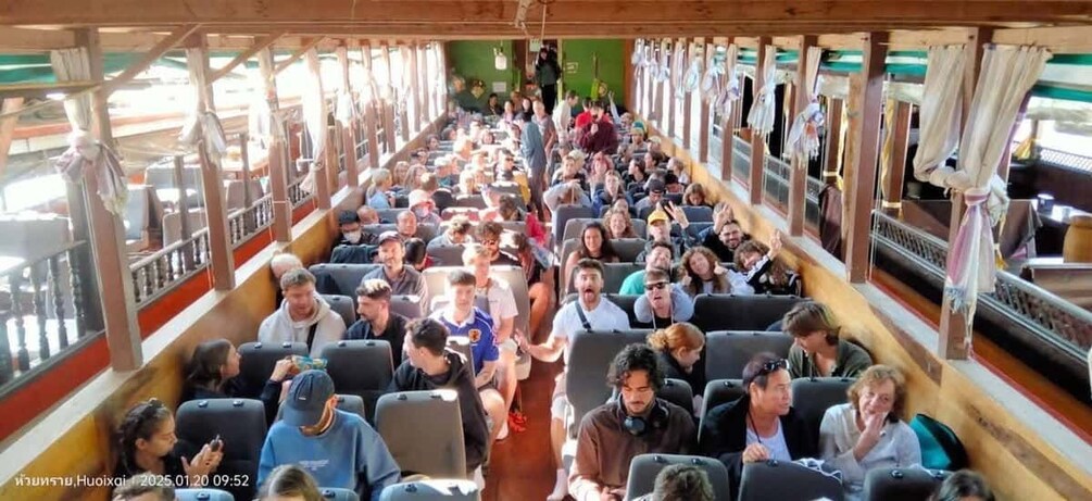 A crowded bus with passengers seated and some standing. 1