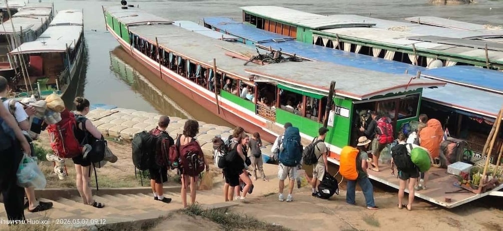 A group of people boarding a colorful boat at a dock. 2