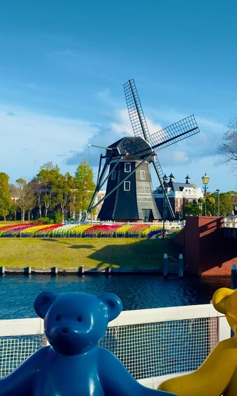 En vindmølle, farverige blomsterbede, et vandelement og en bjørneskulptur. 3