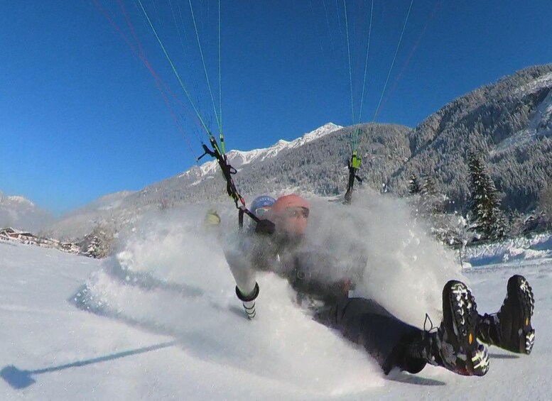 A person in a snowy landscape with a mountainous backdrop, engaged in a water sport activity. 3