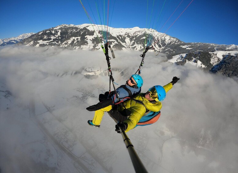 Two people paragliding over a snowy mountain landscape. 1