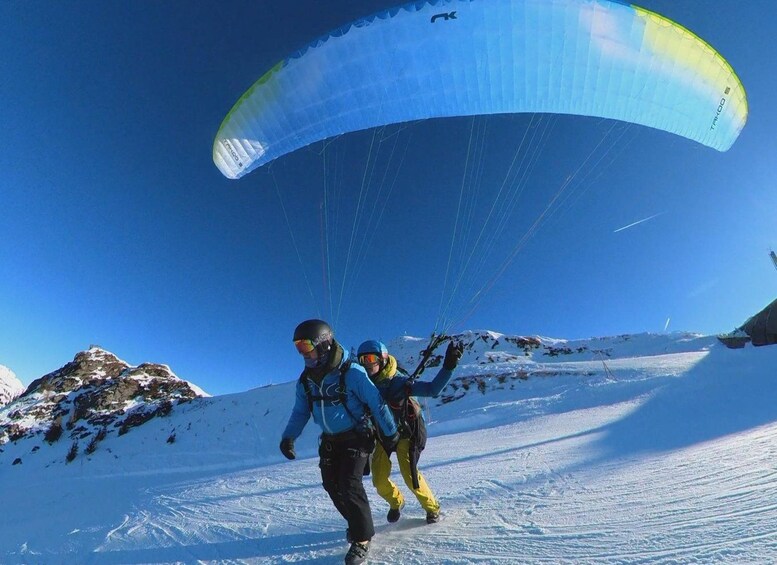 Two people paragliding over a snowy landscape with clear skies. 4