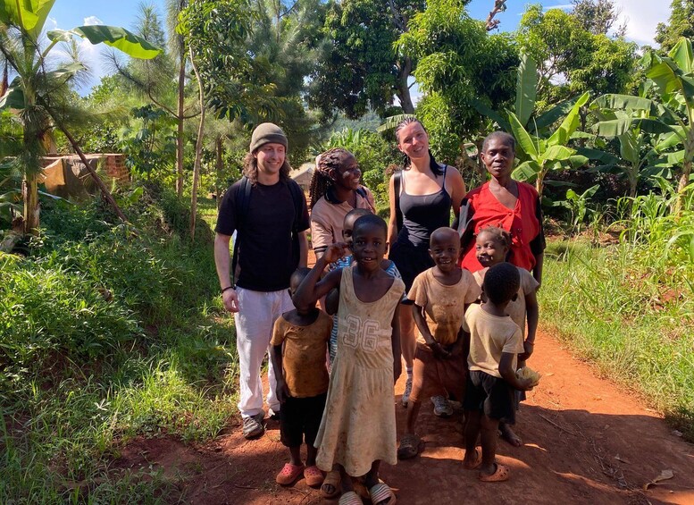 A group of people standing on a dirt path surrounded by lush greenery and trees. 2