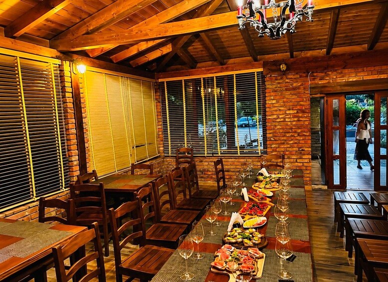 A wooden dining area with tables set for a meal, featuring a variety of dishes and wine glasses. 5