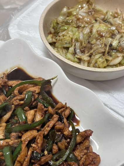 A plate of stir-fried chicken with green peppers and a bowl of cabbage slaw. 4
